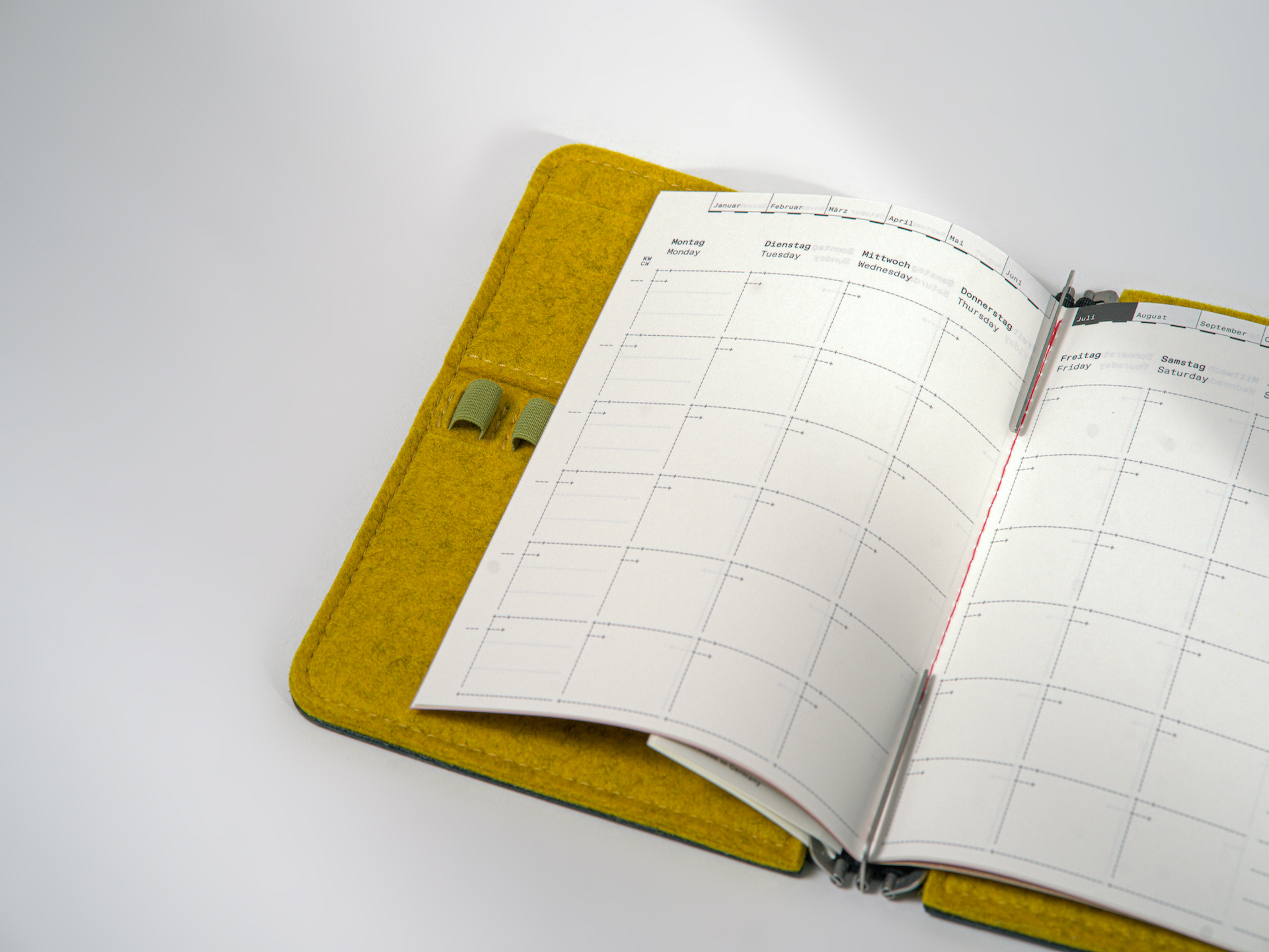 Undated monthly planner in M size (14 × 20 cm) for A5, sewn with red thread, featuring a sturdy cover made from recycled cardboard. 32 pages with colored endpapers.