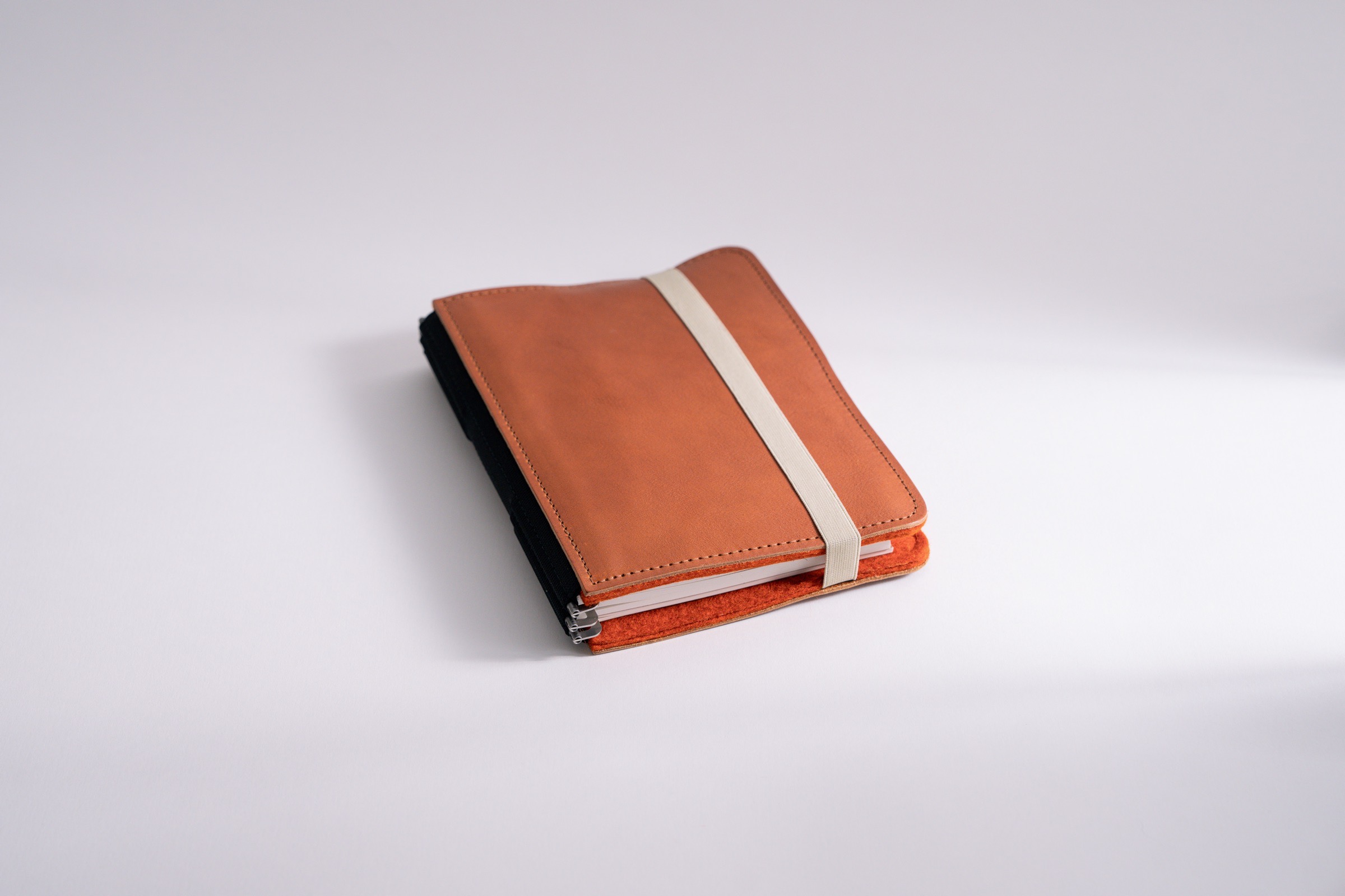 Roterfaden organizer LTD_029 in size M, with rust orange felt inside and light brown leather outside with elastic closure.