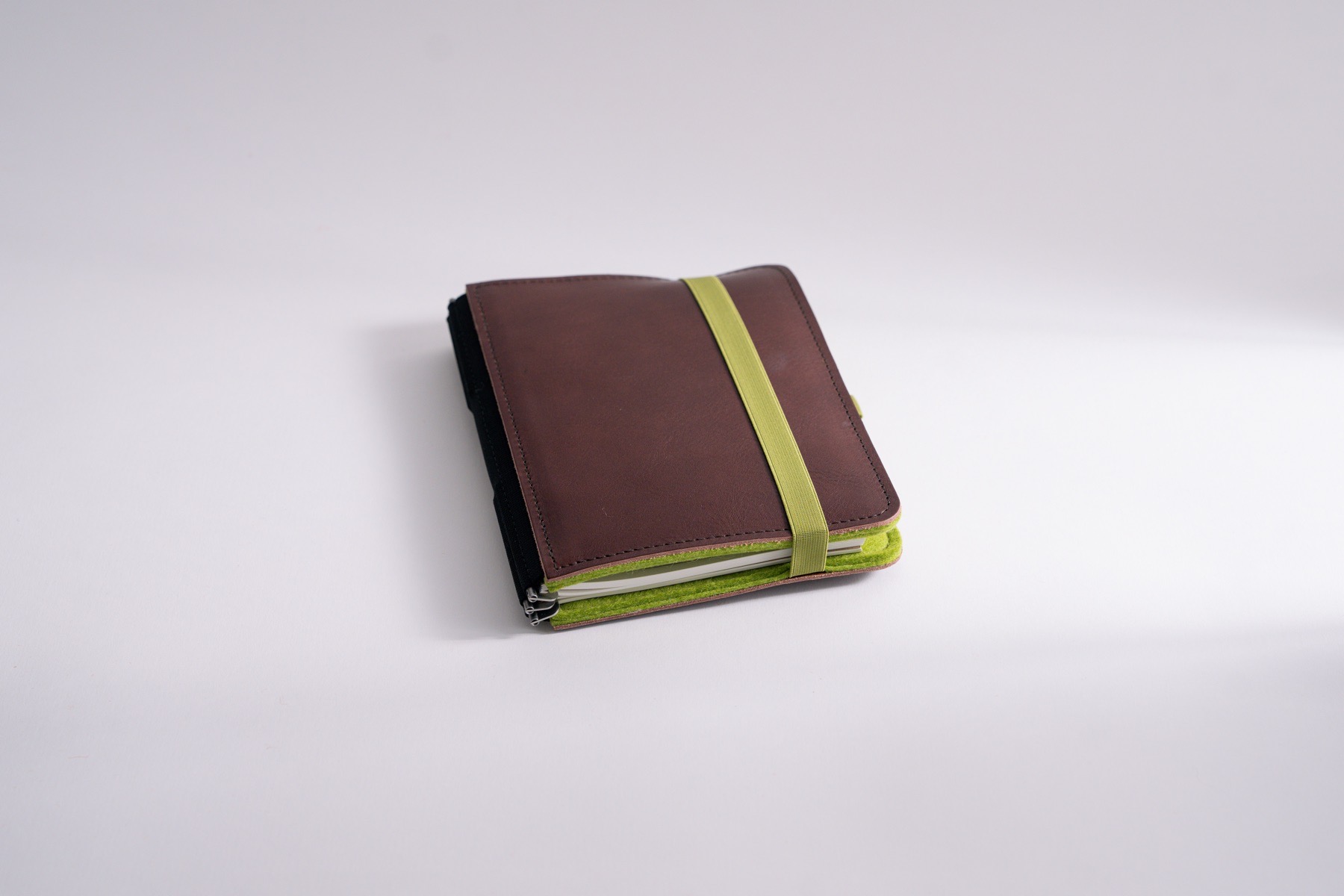 Roterfaden organizer LTD_030 in size M, with lime green felt inside and dark brown leather outside with elastic closure.